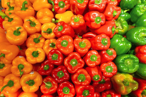 An overhead shot of orange, red, and green bell peppers used to make pepper jelly