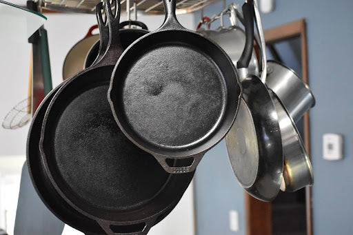 Cast iron skillets hanging from an overhead kitchen pan rack