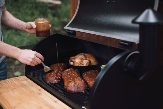 A home cook brushing grilled meats with pepper jelly BBQ sauce