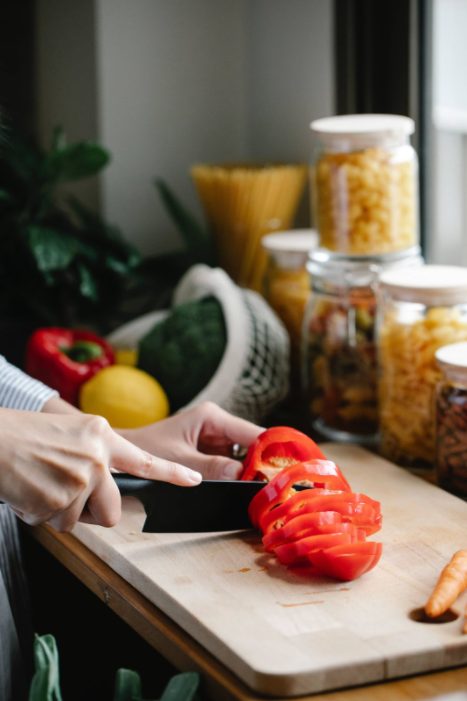 Close-up of a knife slicing a red bell paper on a cutting board