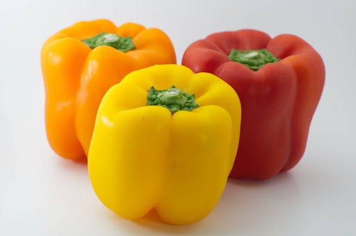 Close-up of three bell peppers, one yellow, one orange, and one red