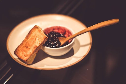 A bowl of pepper jelly dip with a side of toasted bread for dipping