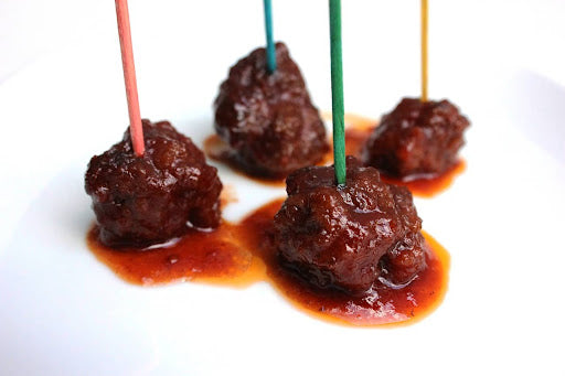 Close-up of four homemade meatballs in a pepper jelly sauce