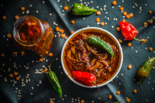 Red and green hot peppers in a bowl of oil