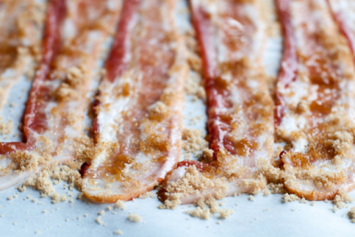 Raw bacon on parchment paper sprinkled with brown sugar