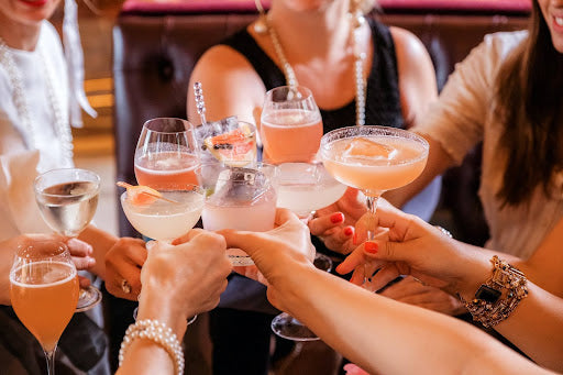 A group of people clinking together glasses filled with spicy mixed drinks